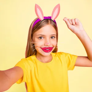 Enfant prenant un selfie avec myFirst Camera Insta Wi, avec des graphismes de filtre facial et d’oreilles de lapin.