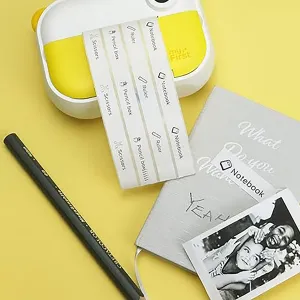 Appareil photo instantané myFirst pour enfants, en jaune, avec bandes photo imprimées, cartes façon carnet et stylo noir sur fond jaune