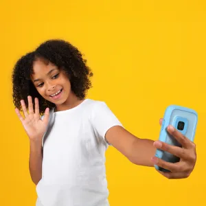 myFirst Camera 50 barnkamera i blått, hållen av ett leende barn som poserar för en selfie mot gul bakgrund