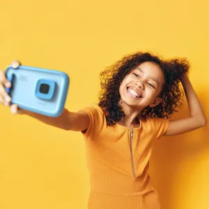 myFirst Camera 50 blå, barnvänlig kamera visas när ett barn tar en selfie mot en gul bakgrund