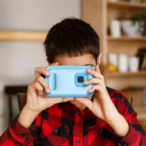 myFirst Camera 50 barnvänlig barnkamera i ljusblått, hålls upp mot ett barns ansikte inomhus