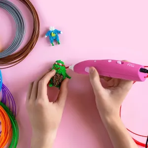 myFirst 3D Pen i rosa, brukt med hendene til å tegne en liten 3D-figur med fargerikt filament