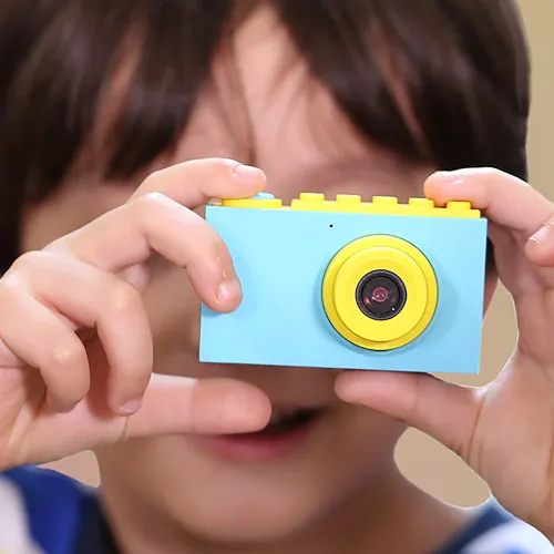 myFirst Camera 2 bērnu kamera zilā un dzeltenā krāsā, turēta rokās, ar kompaktu objektīvu un ūdensizturīgu korpusu
